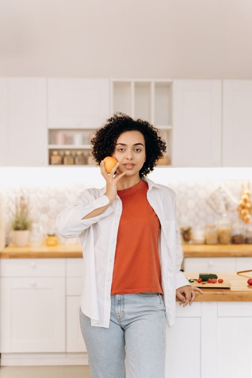 A woman enjoying fresh fruit in a bright kitchen